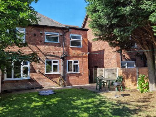 a brick house with a table and chairs in the yard at Perry Road, beautiful large house available for Guests and Contractors Parking wifi in Nottingham