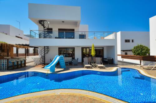 a villa with a swimming pool and a house at Seafront Protaras Villas in Protaras