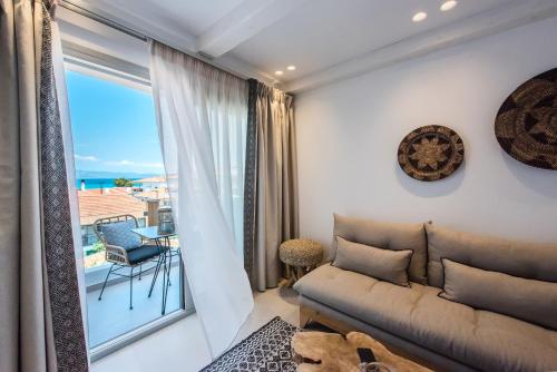 a living room with a couch and a large window at Bohemia Luxury Living in Hanioti
