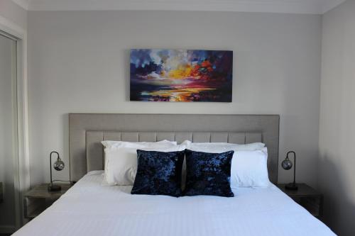 Un dormitorio con una cama blanca con un cuadro encima. en Riverside Apartment, en Ayr