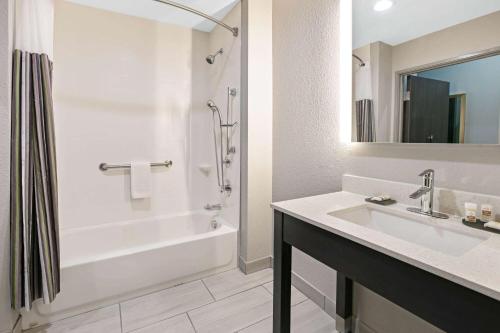 a bathroom with a tub and a sink and a shower at La Quinta Inn & Suites DFW West-Glade-Parks in Euless
