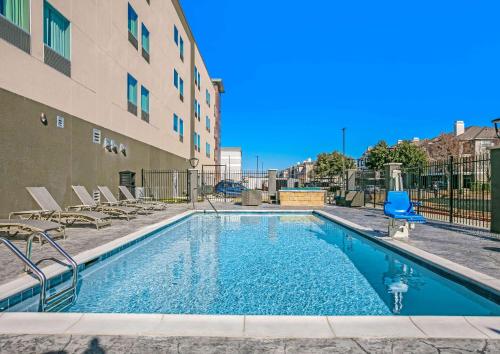 a swimming pool with chairs next to a building at La Quinta Inn & Suites DFW West-Glade-Parks in Euless