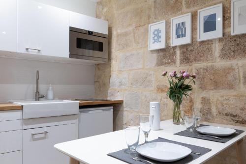 a kitchen with a table with glasses and flowers on it at Design & Cosy - Centre historique Ecusson in Montpellier