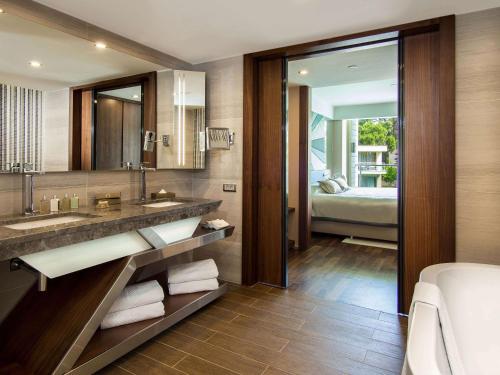 a bathroom with a sink and a mirror and a bed at Rixos Premium Belek - The Land of Legends Access in Belek