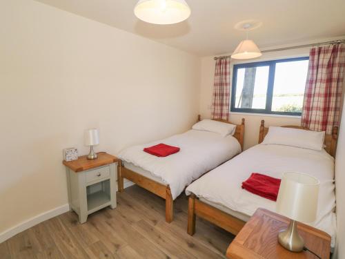 a twin bedroom with two beds and a table at Glan Yr Afon in Holyhead
