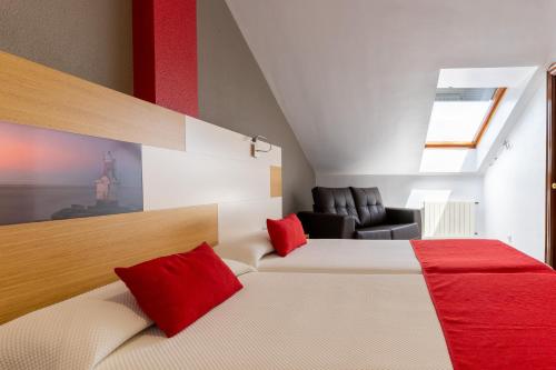 a bedroom with a bed with red pillows and a chair at Chateau La Roca in Sancibrián