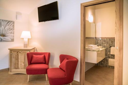 two red chairs and a television in a room at Hotel Aldiola Country Resort in Sant Antonio Di Gallura