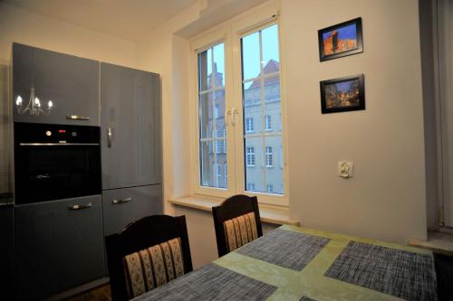 eine Küche und ein Esszimmer mit einem Tisch und einem Fenster in der Unterkunft Długa Street Apartament in Danzig