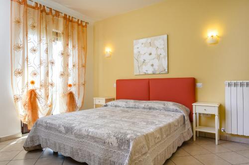 a bedroom with a bed with a red headboard and a window at Residenza Il Rivo in Rivotorto
