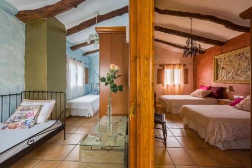 Un dormitorio con 2 camas y una mesa con un jarrón. en Casa rural lo Maset de Carmeta, en Tivenys