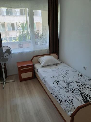 a bedroom with a bed and a window and a fan at Guest House Damyanov in Ravda
