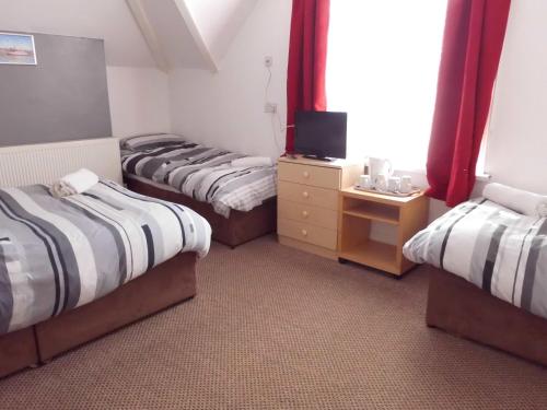 a room with three beds and a tv in it at Jasmine Guest House in Bridlington
