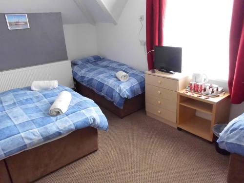 una camera d'albergo con due letti e una televisione di Jasmine Guest House a Bridlington