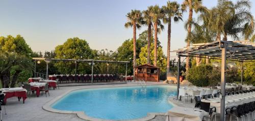 a pool with tables and chairs and a gazebo at B&B Lu Casale in San Cesario di Lecce