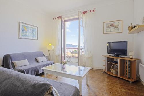 un salon avec un canapé et une télévision dans l'établissement Appartement Mimosas - 3 étoiles - Welkeys, à Hendaye
