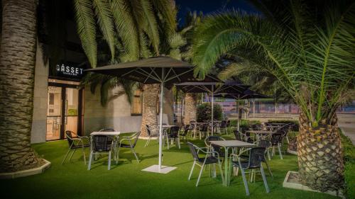 a row of tables and chairs with palm trees in front of a building at Hotel Parque Real in Ciudad Real