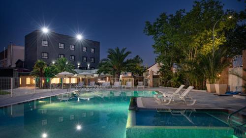 a swimming pool at night with chairs and a building at Hotel Parque Real in Ciudad Real