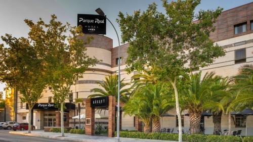 a building with palm trees in front of it at Hotel Parque Real in Ciudad Real