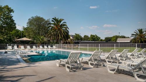 a group of lounge chairs and a swimming pool at Hotel Parque Real in Ciudad Real