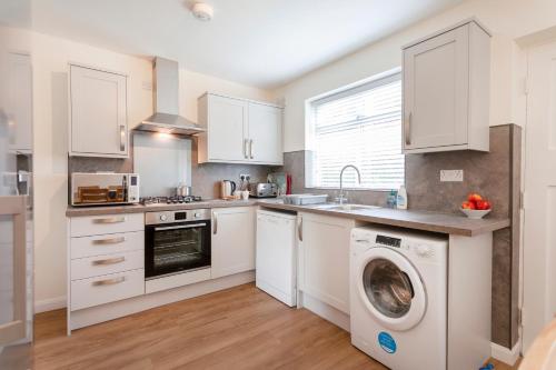 a kitchen with white cabinets and a washer and dryer at CRANBROOK 28 in Nottingham