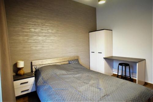 een slaapkamer met een bed, een bureau en een kast bij Marina apartament in Wrocław