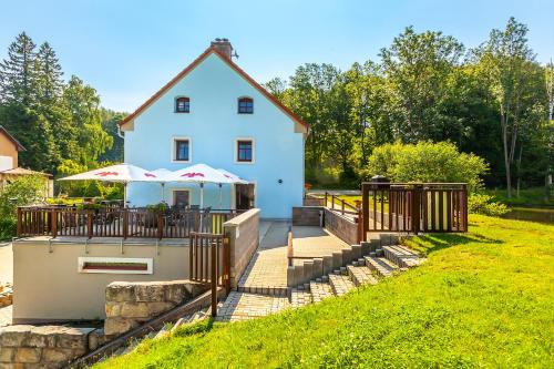 a white house with a deck with an umbrella at Penzion Bačalský mlýn in Morašice