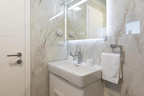a white bathroom with a sink and a mirror at Villa Aurora in Baška