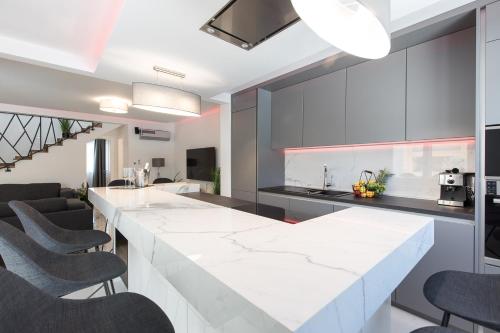 a kitchen with a large white counter and chairs at Villa Aurora in Baška