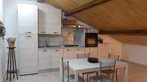 uma cozinha com armários brancos e uma mesa e cadeiras em Case Vacanza Confort Liotta con WIFI free em Giardini Naxos