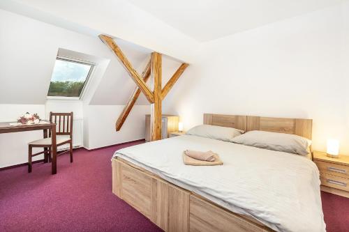 a bedroom with a bed and a desk and a window at Penzion Bačalský mlýn in Morašice