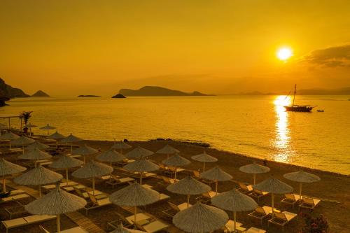 a group of umbrellas on a beach at sunset at Four Seasons Hydra Luxury Suites in Hydra