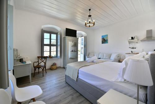 a white bedroom with a large bed and a desk at Hydra Art Suites in Hydra