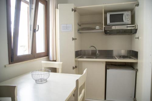 a small kitchen with a table and a microwave at Le Plejadi in Castellammare del Golfo
