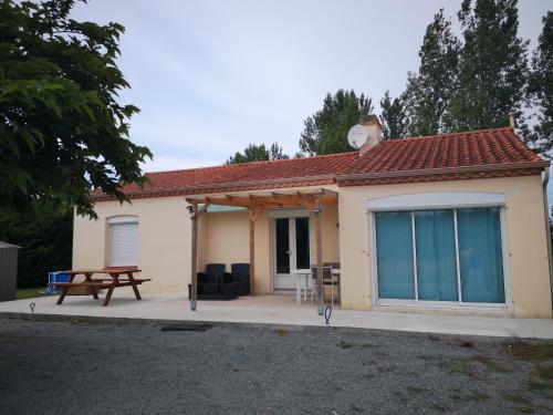 une petite maison avec une table de pique-nique et un banc dans l'établissement chambre chez l habitant, à Saint-Jean-de-Monts