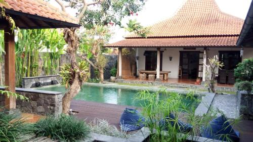 uma casa com piscina em frente a uma casa em Villa Aquin em Surakarta