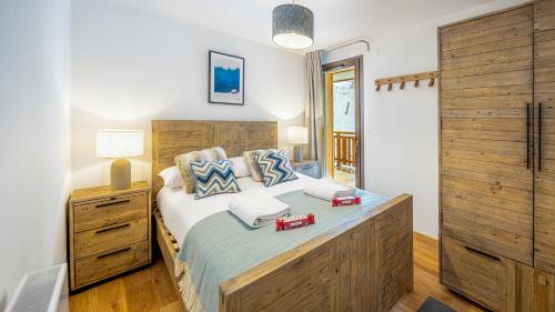 une chambre avec un grand lit avec une tête de lit en bois dans l'établissement Les Freinets - Apt C101 - Châtel, à Châtel