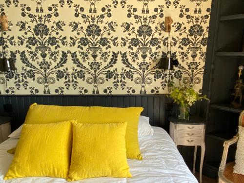 a bedroom with a bed with yellow pillows and a wallpaper at La maison du grand rocher in Ploubazlanec