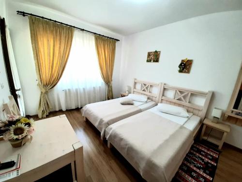 a hotel room with two beds and a window at Dor de Casa in Doljeşti