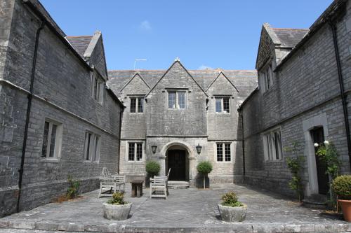 an old stone building with a courtyard with chairs at Mortons Manor in Corfe Castle
