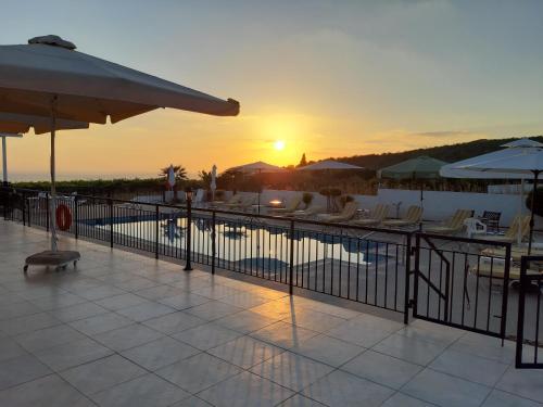 a pool with chairs and a sunset in the background at Nayia Paradise Villa! Best Villa in Cyprus in Paphos City