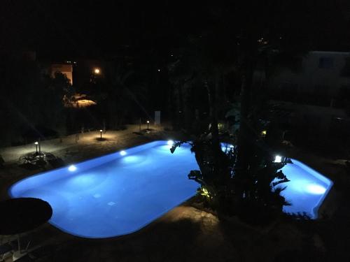 a blue swimming pool at night with a tree at Sea view Apartment Peyia, Paphos in Paphos City