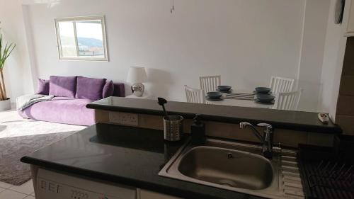 uma cozinha com um lavatório e um sofá na sala de estar em Sea view Apartment Peyia, Paphos em Pafos