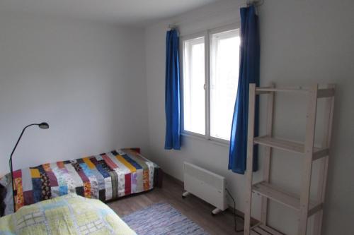 a bedroom with a bed and a window with blue curtains at Budatava nyaraló in Balatonalmádi