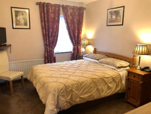 a bedroom with a bed and a chair and a window at Atlantic Guest House in Donegal