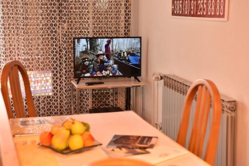 uma sala de jantar com uma mesa com frutas e uma televisão em Apartman Jadranka em Zaprešić