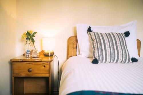 a bed with a pillow and a table with a lamp at The Old Bakery in Kenilworth