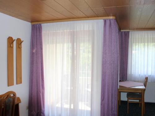 um quarto com uma janela com cortinas roxas e uma secretária em Hotel Garni Silberdistel em Nenningen