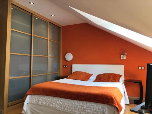 Un dormitorio con una cama con una pared naranja. en Apartamentos Albariño, en Vegadeo