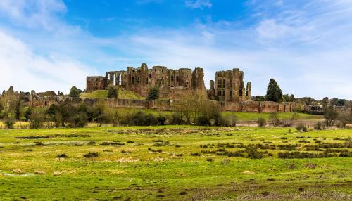 a castle on top of a green field with sheep at The Old Bakery in Kenilworth