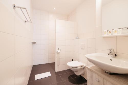a white bathroom with a sink and a toilet at Amsterdam ID Aparthotel in Amsterdam